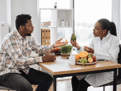 Handsome multiracial man in casual clothes visiting female dietitian in doctors office of medical center. Handsome multiracial man in casual clothes visiting female dietitian in doctors office of medical center.