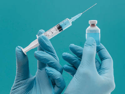 Vaccine bottle and syringe held by doctor with gloves Vaccine bottle and syringe held by doctor with gloves<br />