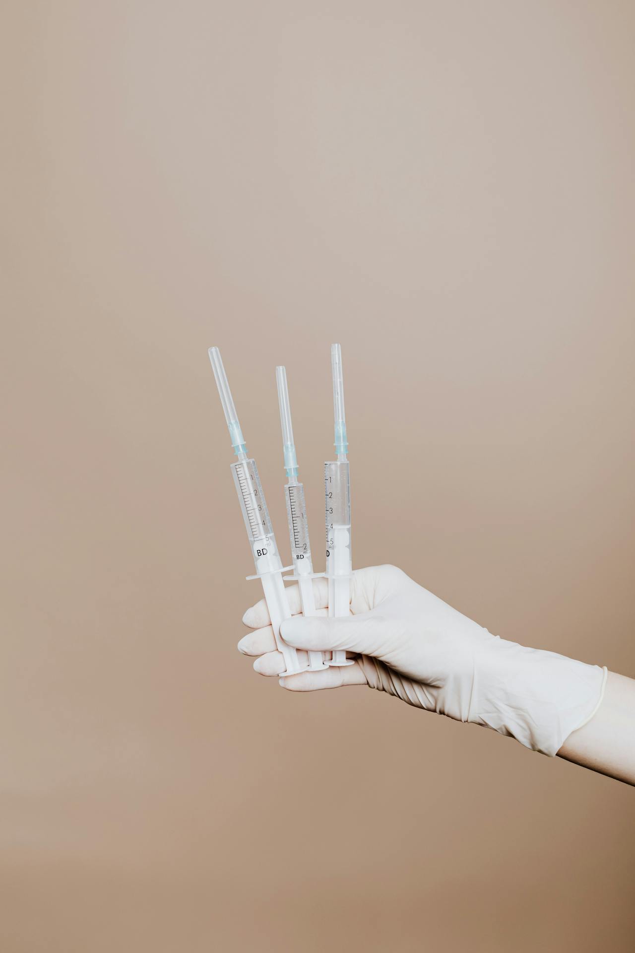 Person Holding Three Syringes with Medicine Person Holding Three Syringes with Medicine<br />